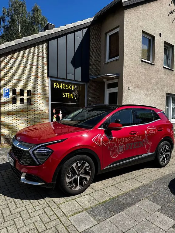 Rotes Fahrschulauto der Fahrschule Stein mit Beschriftung vor dem Büro an der Kaiserstraße in Köln-Porz