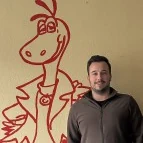 Christopher Stein, Inhaber der Fahrschule Stein, vor dem gemalten Drachen im Unterrichtsraum